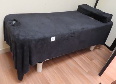 un lit recouvert d'un couvre-lit noir, dans un coin de la pièce