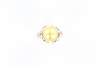 une bague en perle jaune et diamants sur fond blanc