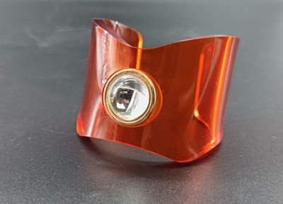 un bracelet orange orné d'un diamant au centre, sur un fond noir