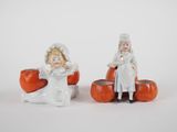two figurines of children sitting on pumpkins