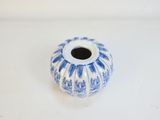 un petit vase bleu et blanc posé sur une surface blanche