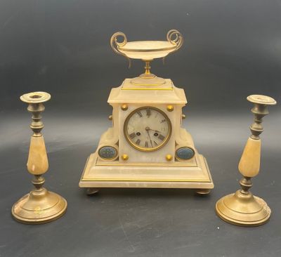 three candles and a clock sitting on a table