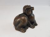 a bronze statue of a dog sitting on a white surface
