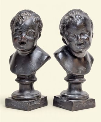 pair of bronze busts of children on pedestals on a white background