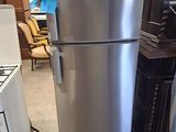 a silver refrigerator in the middle of a room next to a stove