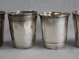 four silver cups are lined up next to each other on a table
