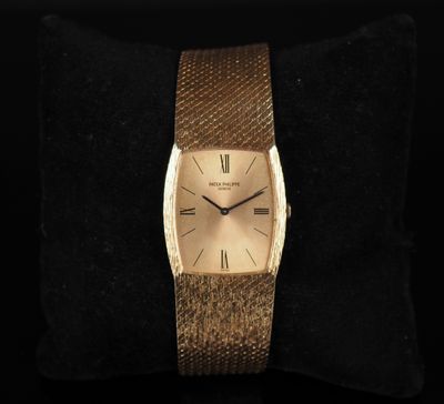 a close up of a gold wrist watch on a black cushion