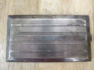 un étui à cigarettes en argent posé sur une table en bois