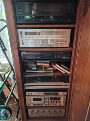 a tall wooden cabinet with many electronics on top of it