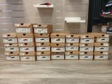 a pile of boxes of shoes sitting on top of a wooden floor