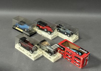 quatre petites voitures sont exposées dans une vitrine posée sur une surface grise