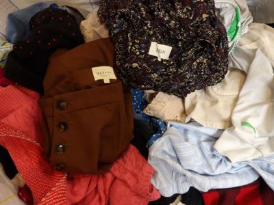 a pile of clothes that is sitting on a bed