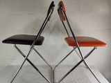 two folding chairs that are sitting on a white table