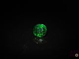 a close up of a green glass ball on a black surface