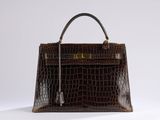 a close up of a brown alligator skin handbag on a white surface