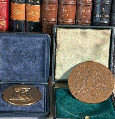 a gold medal sitting in a case next to a pile of books