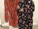 deux robes pour femmes suspendues à un portant devant un mur blanc