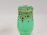 a green vase with a gold rim sitting on a white surface