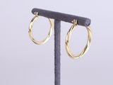 un gros plan sur une paire de boucles d'oreilles créoles en or posées sur un présentoir