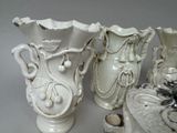 three white vases sitting next to each other on a table