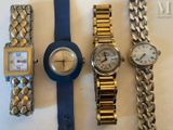 trois montres et un bracelet sont posés sur une surface blanche