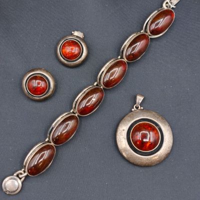 une photo d'un ensemble composé d'un collier, d'un bracelet et d'une bague sertis de pierres rouges