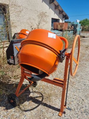 an orange cement mixer sitting in front of a building