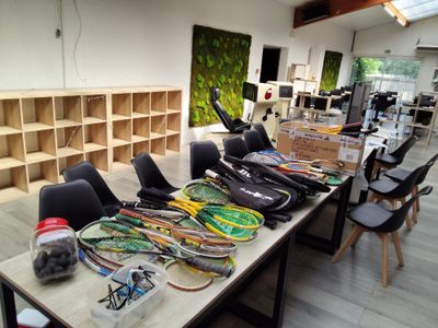 Plusieurs raquettes de tennis sont alignées sur une table dans une pièce.