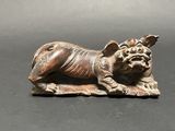 statue of a dog lying on its back on a black surface