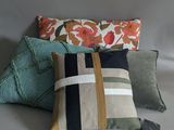 three pillows with different colors and patterns on them on a gray background