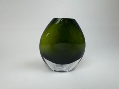 un vase en verre vert posé sur une surface blanche