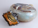 a small box with a lid sitting next to a small object