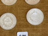 six types de pièces différents posés sur une table, accompagnés d'une étiquette de prix