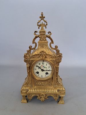 a gold clock sitting on a table with a white background