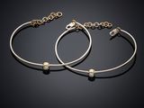 a pair of gold and silver bracelets on a black background