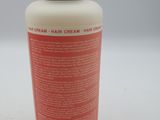 a close up of a bottle of hair cream on a white surface