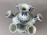 a blue and white vase with four cups on it
