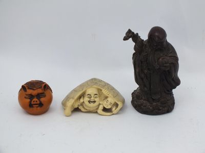 deux petites figurines sculptées et une citrouille sculptée posées sur une surface blanche