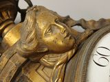 a gold clock with a woman ' s face on it