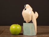 a white bird sitting on a block next to an apple