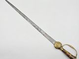 a close up of a knife with a gold handle on a white surface