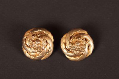 une paire de boucles d'oreilles en forme de fleurs de couleur dorée sur fond noir