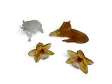 three figurines of animals and flowers on a white surface