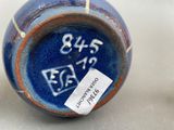 a blue and orange vase with a tag on it