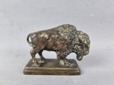 statue en bronze représentant un bison sur un socle, sur fond blanc