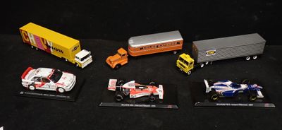 Plusieurs petites voitures et camions sont alignés sur une surface noire