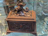 une boîte en bois ornée d'un oiseau, exposée dans une vitrine