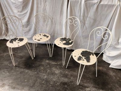 three white chairs with black spots on them sitting in front of a curtain