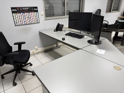 a desk with two monitors and a chair in a room