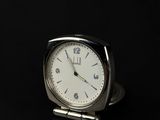 a small silver clock sitting on a black surface